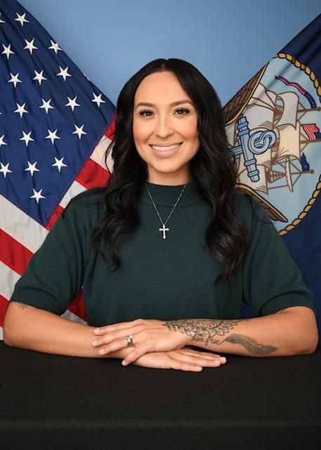 A posed picture of Salena McAleavey in front of the United States and US Navy flags.